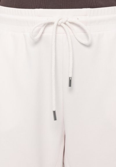 Baltas sporta bikses ar stringa jostu, ar teksturētu audumu un sudraba metāla akcentiem stringa galiņos.