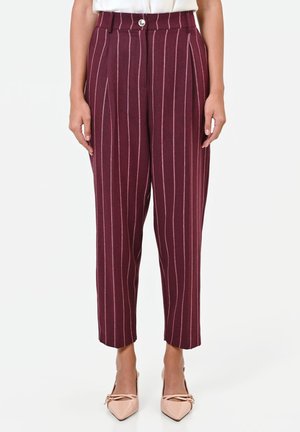 Pantaloni bordeaux a vita alta con righe verticali bianche, chiusura con bottone e zip, indossati con tacchi a punta rosa chiaro.