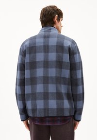 Blauwe en grijze wollen shirtjasje van een mengsel met een groot ruitpatroon, hoge kraag en verlaagde schouders, met een gladde textuur en zijsplitten.