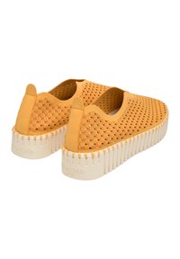 Scarpe gialle slip-on realizzate in materiale testurizzato con un design perforato. La suola in gomma bianca presenta dettagli scanalati.