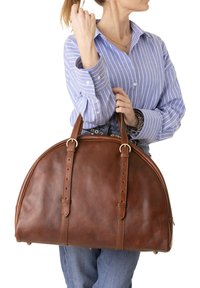 Bruine leren handtas met een ronde vorm, voorzien van twee lange riemen met gouden accenten en zichtbare steekdetails.