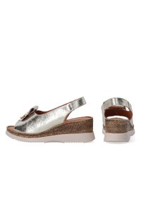 Metalen zilveren wedge sandalen met een slingback ontwerp, voorzien van een textuur kurken hak en een decoratieve strik aan de voorkant.