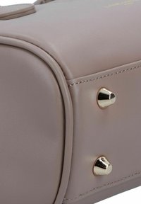 Borsa in ecopelle rosa chiaro con cuciture visibili, angoli arrotondati e borchie in metallo dorato sui lati. Presenta una texture liscia.