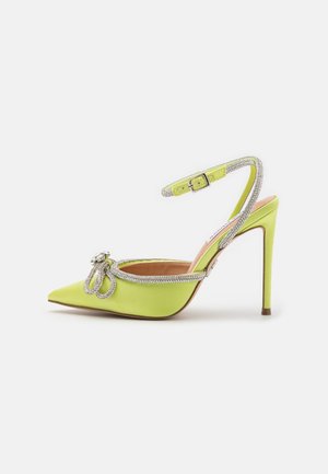 Green satin high-heeled slingback shoe with pointed toe, rhinestone accents, and a decorative bow detail. Adjustable ankle strap included.