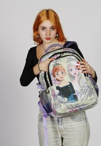 Mochila multicolor con personajes de dibujos animados sobre un fondo floral, hecha de tela, con correas ajustables y un bolsillo con cremallera en la parte delantera.