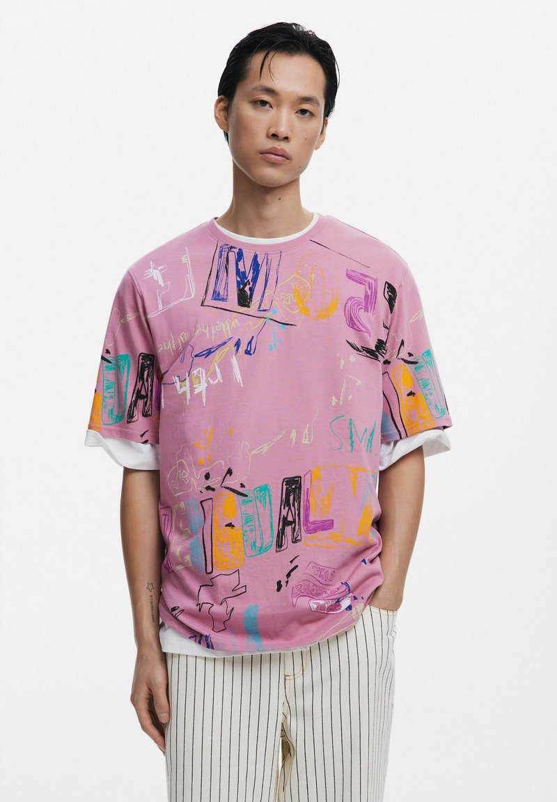Roze oversized t-shirt met kleurrijke grafische ontwerpen, voorzien van schetsen en tekst in verschillende felle kleuren. Korte mouwen met een witte rand.