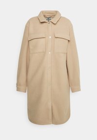 Světle béžová flísová košile s límečkem, dvěma náprsními kapsami a zapínáním na patentky. Dlouhé rukávy s manžetami na knoflíky.