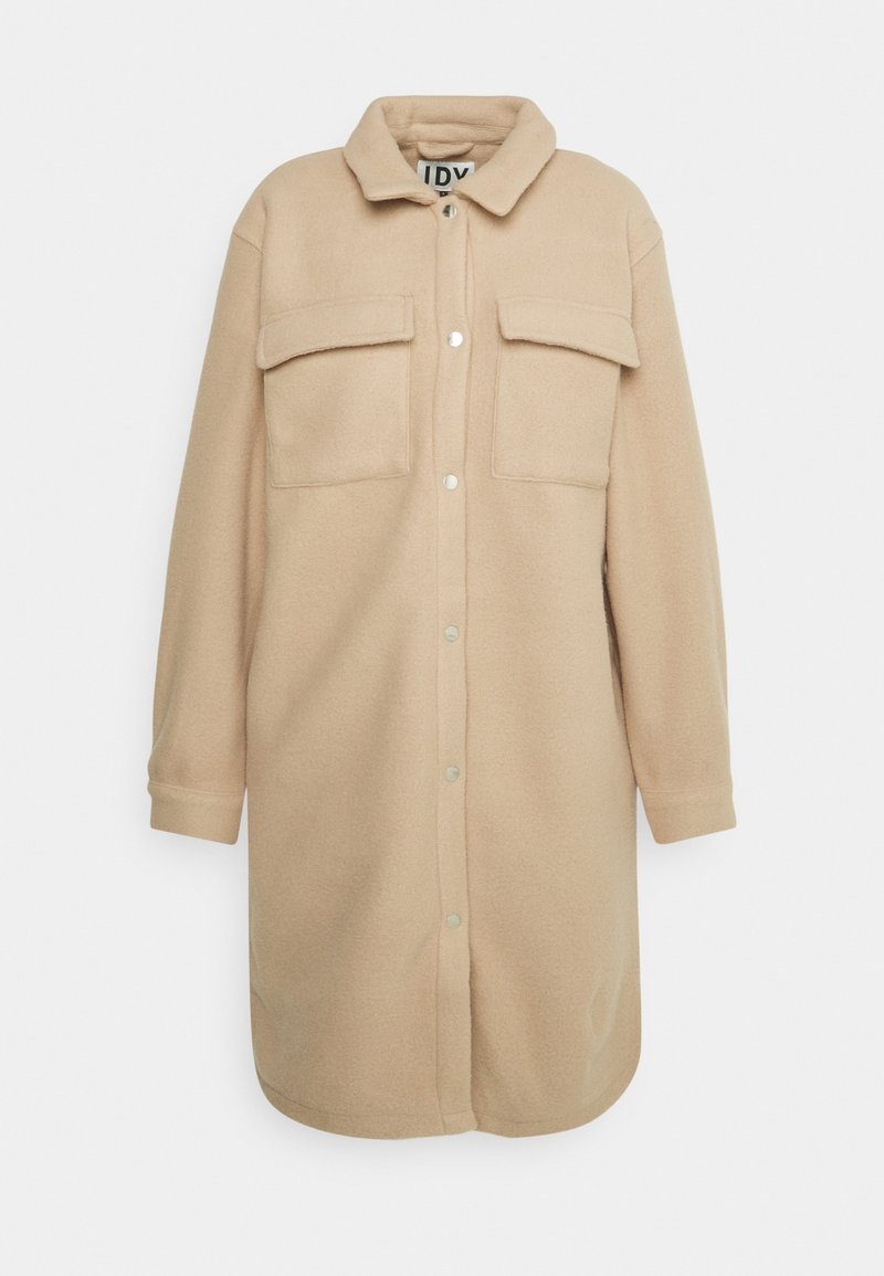 Světle béžová flísová košile s límečkem, dvěma náprsními kapsami a zapínáním na patentky. Dlouhé rukávy s manžetami na knoflíky.