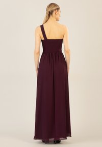 Lang, ärmelloses, burdeosfarbenes Kleid mit einem gerafften Oberteil und einem fließenden Rock. Ein Schulterträger, weicher Stoff und knöchellanger Saum.