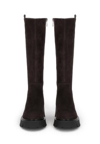 Knee-high boty vyrobené z tmavě hnědé semišové kůže, s designem na obutí, které mají silnou černou gumovou podrážku a boční zipy.