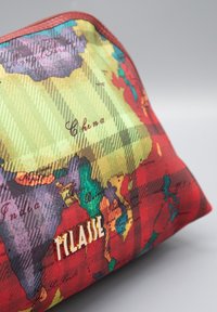 Borsa rossa e verde con stampa della mappa del mondo, con dettagli hardware dorati che formano la scritta "TILAAJE." Realizzata in tessuto strutturato con colori vivaci.