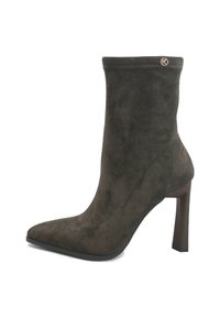 Stivaletto in suede marrone scuro con punta affusolata, tacco a blocco alto e piccolo logo metallico rotondo vicino al bordo superiore.