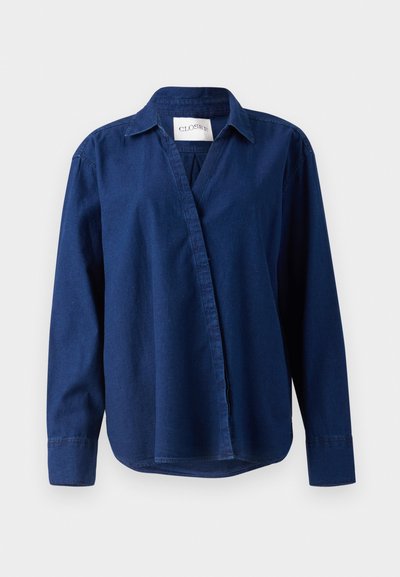 Dunkelbluse, langärmlig, aus Denim, mit spitzem Kragen und knopflosem Frontverschluss. Weiche Textur mit lässigem Schnitt.