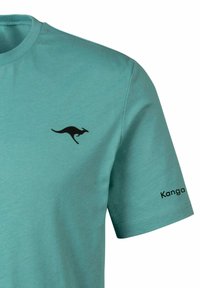 Türkisfarbendes Baumwoll-T-Shirt mit schwarzem Känguru-Logo auf der linken Brust und "Kanga"-Text auf dem rechten Ärmel gedruckt.