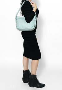 Borsa a spalla in morbido cuoio blu chiaro con manico intrecciato. La borsa presenta una texture liscia e una forma strutturata, ideale per l'uso quotidiano.
