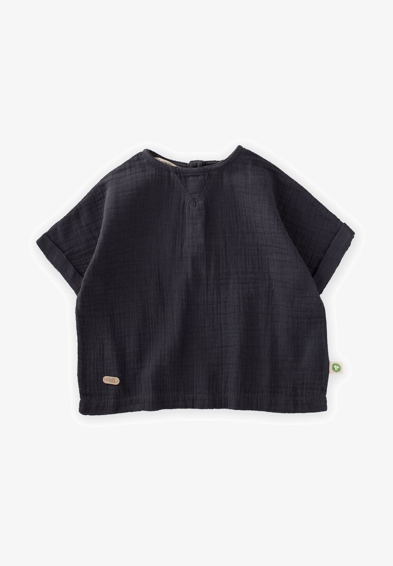 Tumšs, īsām piedurknēm tops no mīkstas, teksturētas auduma. Tam ir V formas kakla izgriezums un sarullēti piedurkņu gali, kā arī neliels logo uzlīmē sānos.