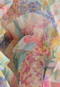 Tessuto in rete trasparente colorato con motivi floreali in tonalità pastello di rosa, blu e giallo, caratterizzato da bordi arricciati e un aspetto strutturato.