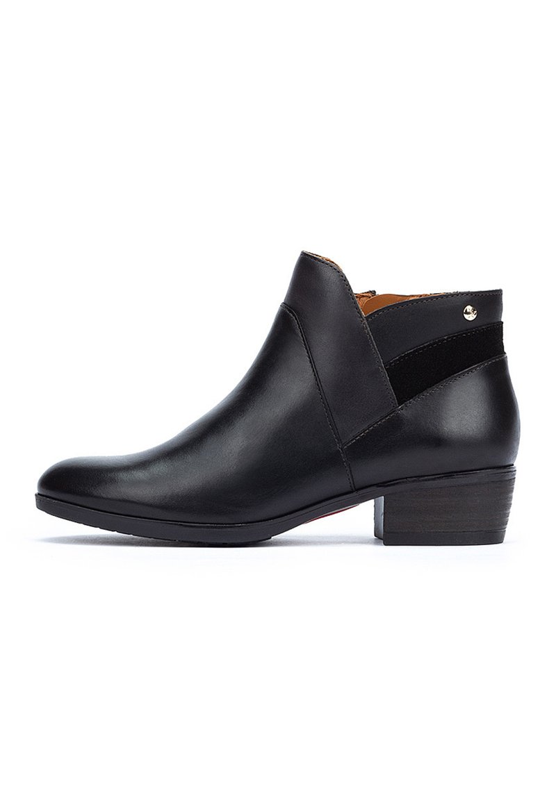 Bottine noire en cuir avec un bout rond, un petit talon empilé et une sangle d'accent en daim. Fermeture à glissière sur le côté et petit détail métallique.