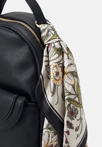 Schwarzer strukturiertes Leder-Rucksack mit einem floralen Seidenschal, der am Griff gebunden ist, in lebendigen Farben und komplexen Details. Mit goldenen Beschlägen.