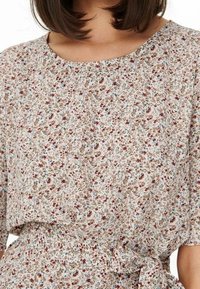 Květinová blůza, světle béžový základ s malými červenými, modrými a hnědými květy, krátké rukávy, kulatý výstřih, nařasený pas se stahovací šňůrou.