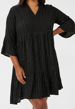 Zwarte jurk met zilveren verticale strepen, driekwart klokmouwen en een gelaagde, loszittende rok.