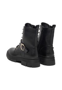 Melni ādas potītes zābaki ar masīvu zoli, ar auklām, sānu rāvējslēdzēju un dekoratīvu sprādzi uz siksniņas, pievienojot papildu akcentu.