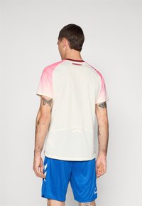 T-shirt de sport pour homme avec une base blanche, un dégradé rose aux épaules, des manches courtes et un tissu texturé.
