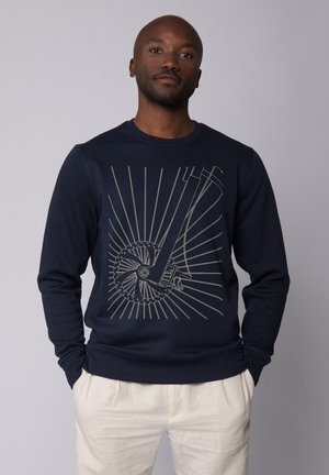 Marine sweatshirt met lange mouwen en een ronde hals, voorzien van een beige grafisch ontwerp van een wiel met stralen die daaruit voortkomen.