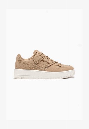 Beige lavtop sneaker med hvid sål, snørelukning foran, perforeret sidepanel og mærket prægning på hæl og side.