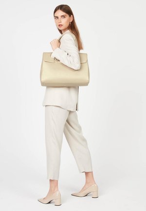 Sac à main en cuir beige avec un design structuré, doté d'un haut plat, de deux poignées courtes et de détails de couture saillants.