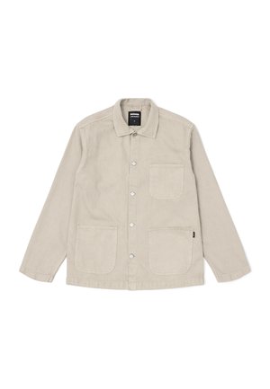 Chaqueta de color beige claro hecha de algodón, con un cierre de botones en la parte delantera, cuello punto y dos grandes bolsillos frontales con detalles de costura visibles.