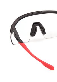 Ochelari de sport negri cu lentile transparente, cu suporturi pentru nas din cauciuc și brațe de temple texturate roșii. Dispune de un design elegant și unghiular.