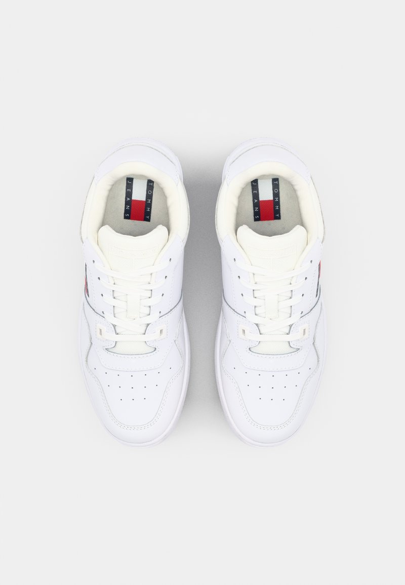 Sneaker bianche in pelle con design a lacci, punteggiatura sulla parte anteriore e marchio a strisce rosse e blu sulla linguetta. Texture liscia, stile low-top.