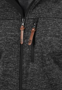 Gray zip-up hoodie with a textured fabric, featuring black zippers and brown leather pull tabs. No visible logos or patterns.