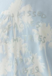 Helle blaue Stoff mit weißen Palmen-Silhouetten und silbernem Text "Sun Kissed Beaches Palm Trees & Happy Vibes".