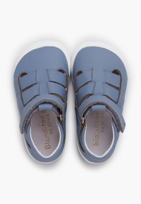 Sandalias de cuero azul con un diseño de punta cerrada, que cuentan con una correa y acentos trenzados, complementadas por una suela de goma blanca.