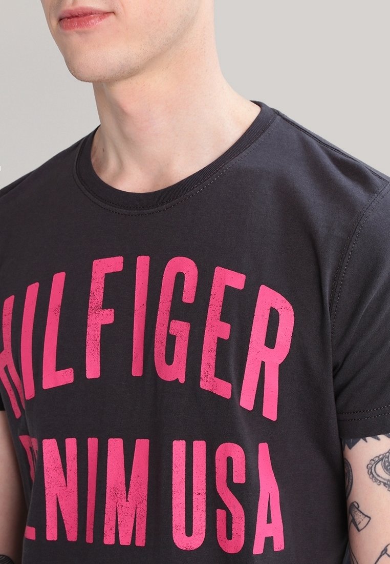 Černé bavlněné tričko s výrazným růžovým potiskem "HILFIGER DENIM USA". Krátké rukávy, kulatý výstřih a hladká textura s jemnými detailem prošití.