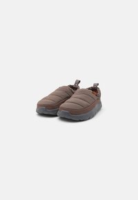 Bruna vadderade slip-on skor med en texturerad överdel, med elastiska sidopaneler och en grå gummisula för flexibilitet och komfort.
