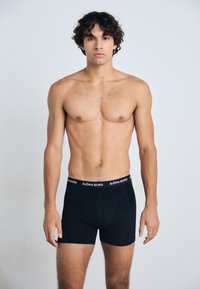 Schwarze Boxershorts aus weichem Stoff mit elastischem Bund, der das Logo "BJÖRN BORG" zeigt. Angenehme Passform mit glatter Textur.