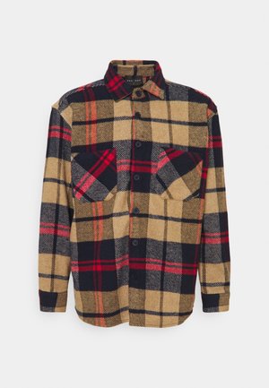 Langärmliges Hemd mit Knopfleiste mit beigem, schwarzem und rotem Karomuster und zwei Brusttaschen vor schlichtem Hintergrund.