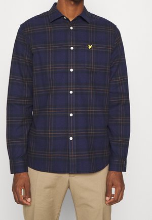 Chemise à carreaux marine avec des accents orange et jaune, manches longues, poche poitrine et boutons blancs. Fabriquée en tissu texturé.