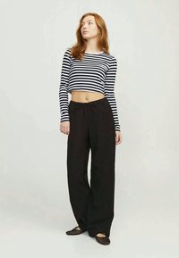 Calças largas pretas combinadas com um top de manga longa aos riscas preto e branco cropped. Tecido suave com um corte descontraído, adequado para vestuário casual.