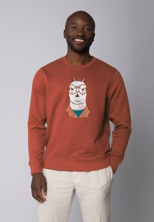 Roestkleurige sweatshirt met een lama-graphic die een bril en een jack draagt. Zachte textuur, een ronde hals en ribgebreide boorden en onderkant.