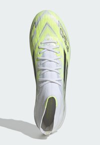 Λευκά και νέον κίτρινα ποδοσφαιρικά παπούτσια με σχέδιο κάλτσας υψηλού αστραγάλου, λευκά κορδόνια και υφή σε σχήμα βέλους στην κορυφή.