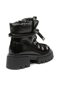 Botas altas negras de material brillante, con cuello acolchado, suela gruesa y resistente, ojales de metal y cordones texturizados.