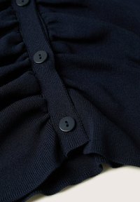 Cárdigan de punto azul marino con un diseño con volantes, cinco botones negros en el frente y un acabado texturizado.
