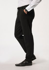 Zwarte broeken met een gladde textuur, voorzien van een elastische taille met koord, zijzakken en omgeslagen zoom, gecombineerd met glanzende zwarte dubbel-monkschoenen.
