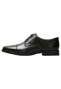 Zapato de vestir de cuero negro con punta afilada, diseño sencillo de cordones, suela plana de goma y detalles de costura mínimos.