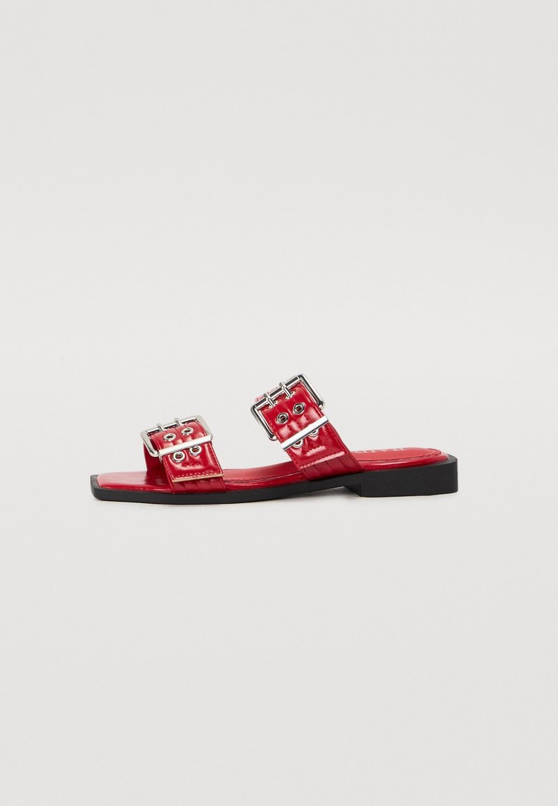 Sandales plates en cuir verni rouge avec deux boucles carrées, semelle noire plate et motif texturé horizontal sur les brides.
