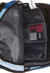 Intérieur d'un sac à dos bleu et noir avec une texture lisse, une poche avec une étiquette et un séparateur à motifs pour l'organisation.